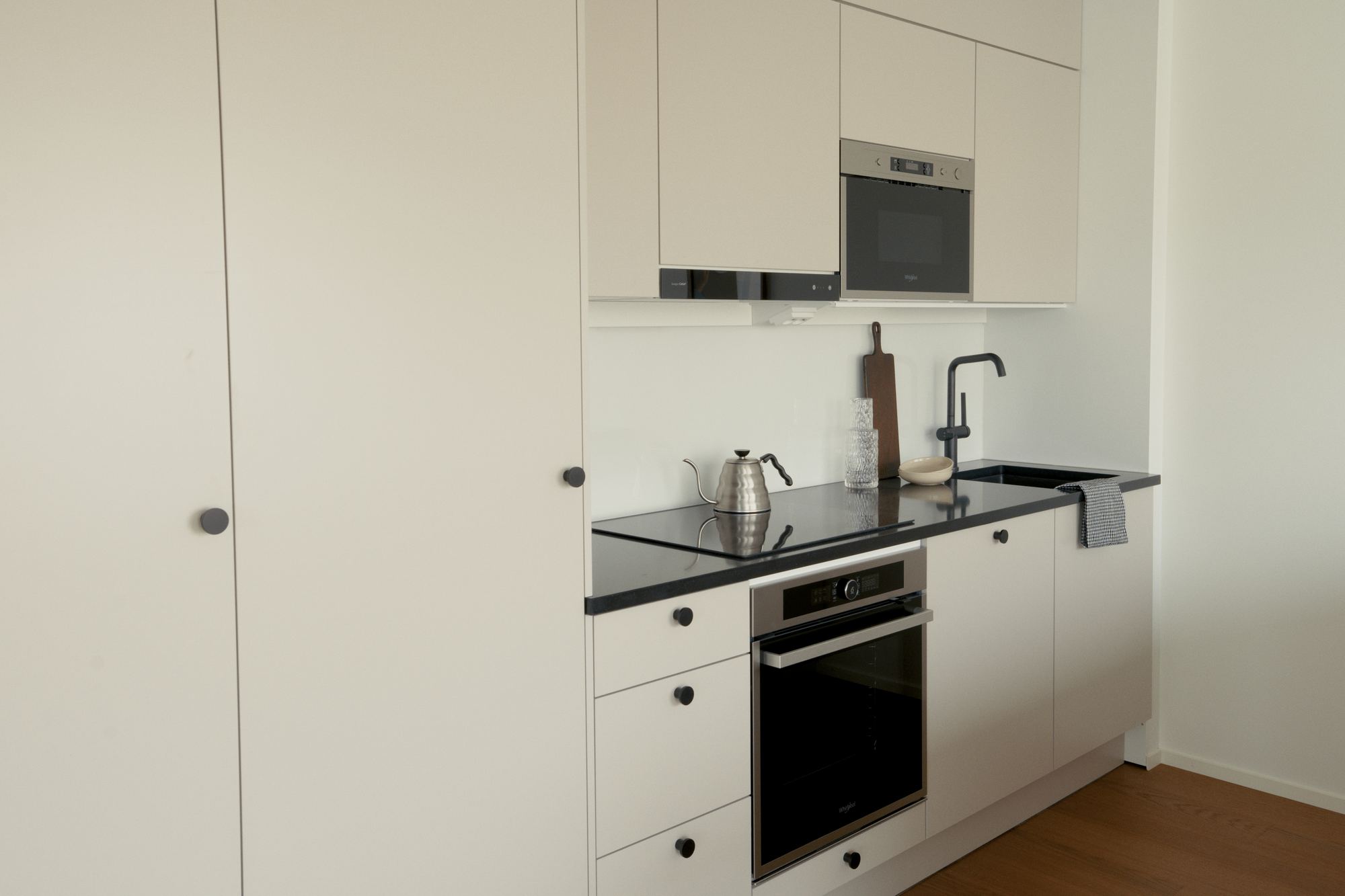 A white kitchen with a black worktop in a finished home in Keskuspuiston Grand