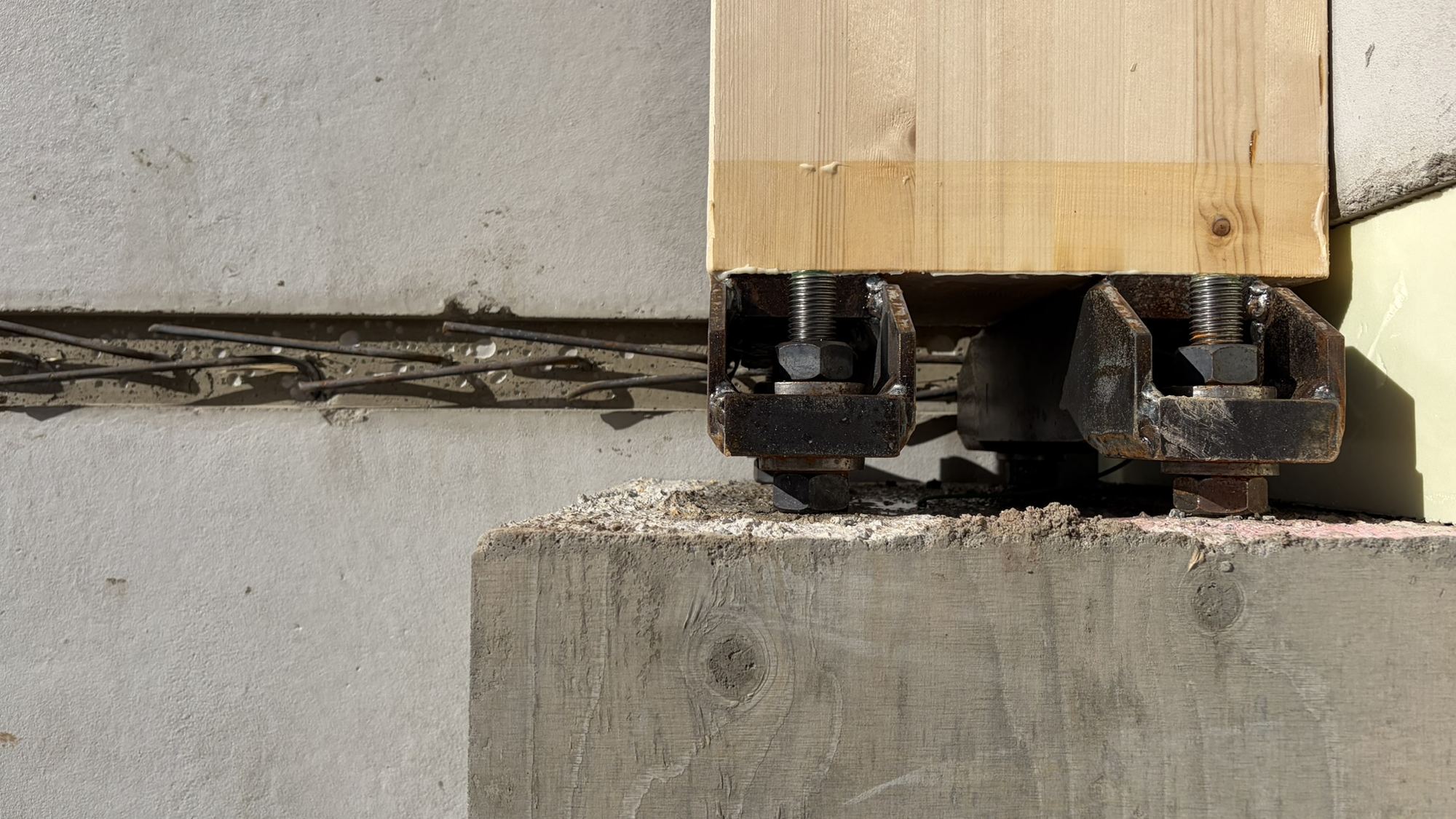 The foot of a glulam column bolted to its concrete foundation